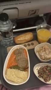 Flugzeugessen auf Klapptisch mit Getränken und Brot.