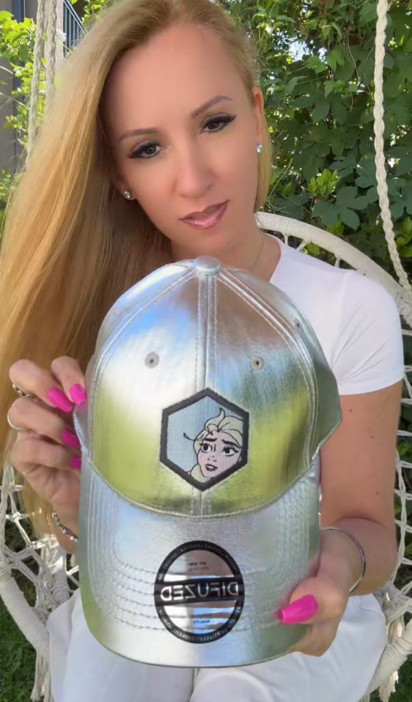 Frau hält silberne Mütze mit Gesichtsmotiv.