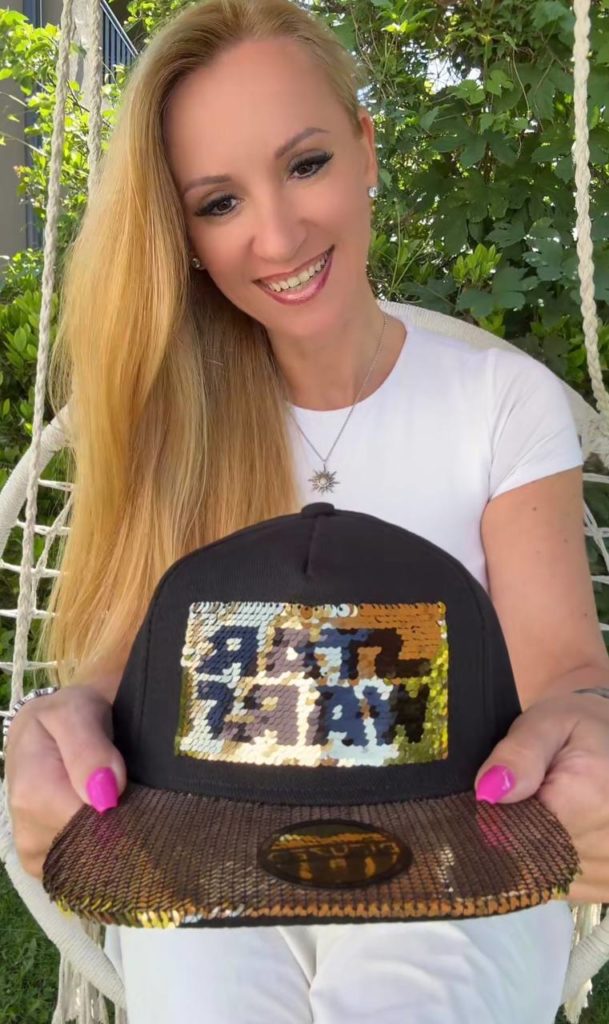 Frau mit glitzerndem Baseball-Cap in der Hand