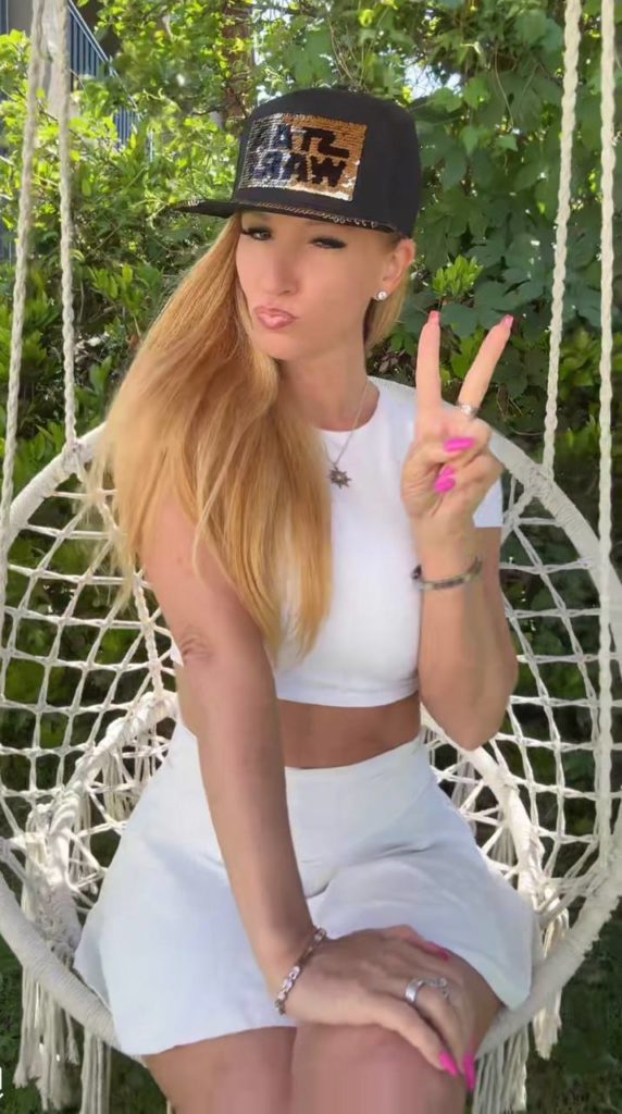 Frau auf Schaukel im Garten mit Victory-Zeichen