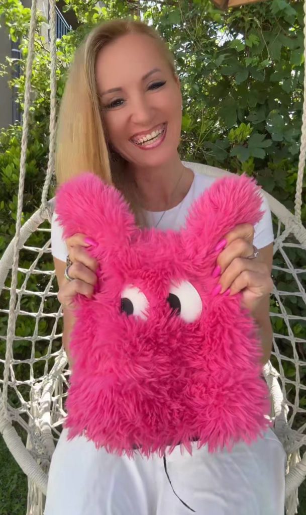 Lächelnde Person mit pinkem Plüschkuscheltier