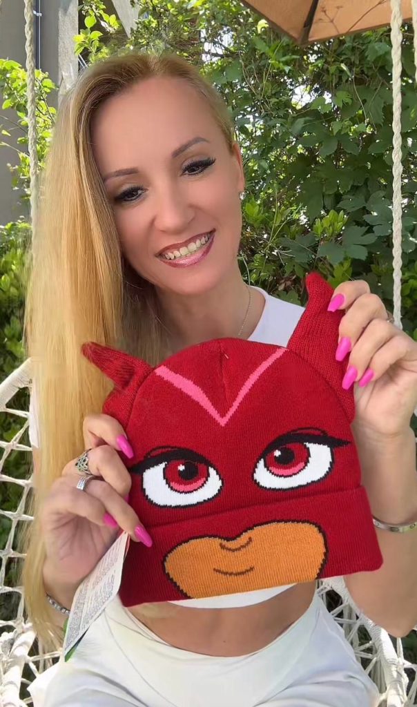 Frau hält rote Strickmütze mit Tiergesicht.