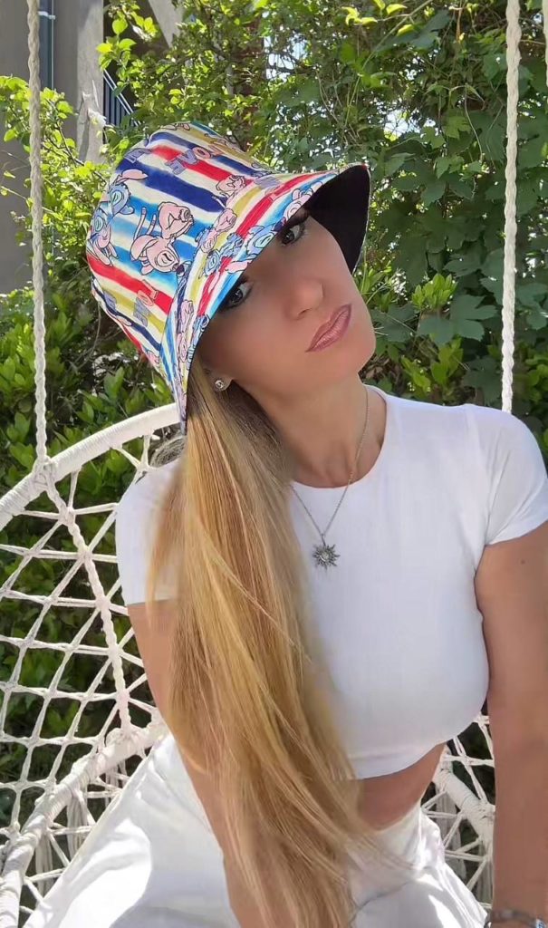 Frau mit Sonnenhut im Garten schaukelt