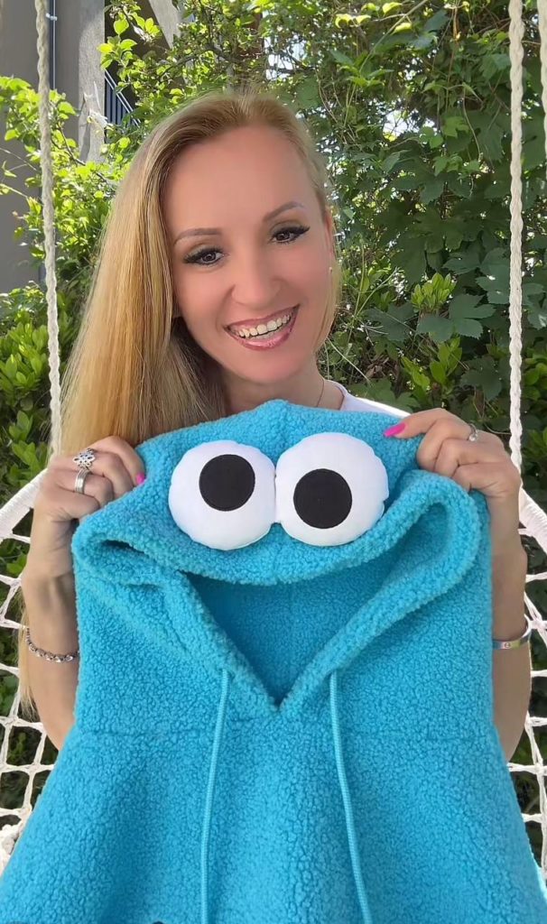 Frau mit blauem Hoodie und großen Augen darauf.