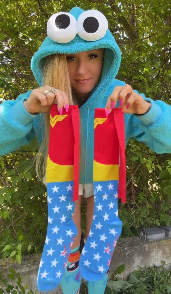 Person mit Kapuzenpulli hält bunte Socken hoch