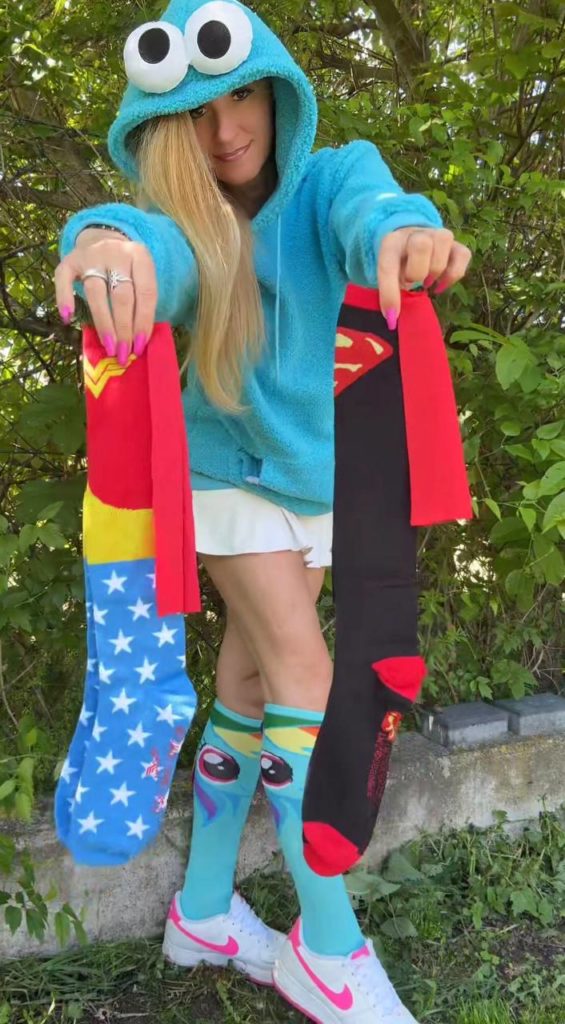 Frau in blauem Hoodie zeigt bunte Socken.