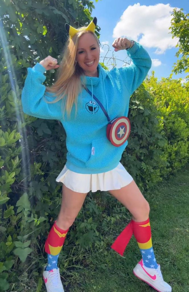 Frau in buntem Cosplay-Outfit vor grünen Hintergrund.