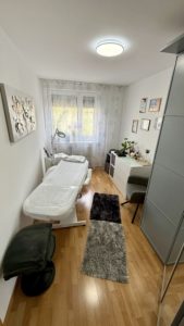 Modernes Behandlungszimmer mit Liege und Pflanzen.