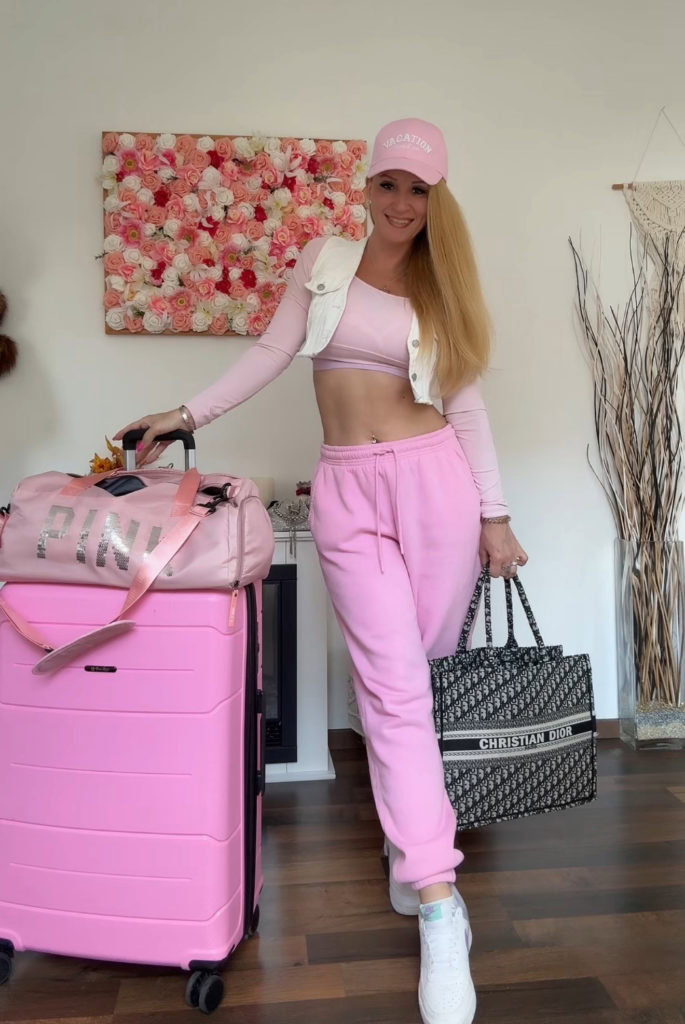 Frau mit rosa Gepäck und Kleidung lächelnd