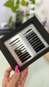 Eyelash-Extensions in schwarzer Verpackung, von Hand gehalten.